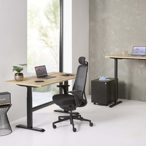 Modern office setup with adjustable desk, chair, and laptop.